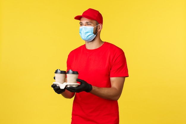 Takeaway delivery, food and drinks, covid-19 quarantine and preventing virus concept. Nice smiling courier bring order, drive through employee handing coffee to customer, wear medical mask