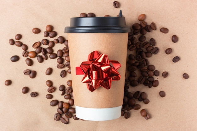 Takeaway paper cup of coffee with a festive red bow.