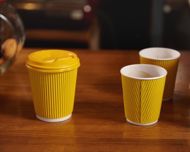 Takeaway paper cups with hot coffee on a wooden surface in the cafe