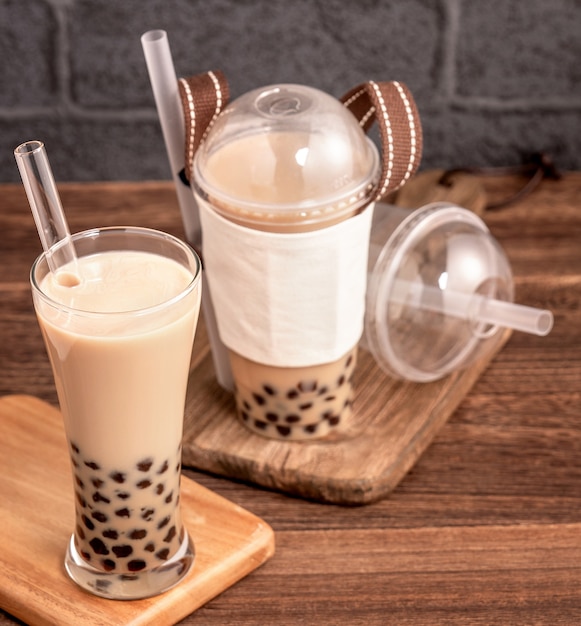 Takeout with disposable item concept popular Taiwan drink bubble milk tea with plastic cup and straw on wooden table