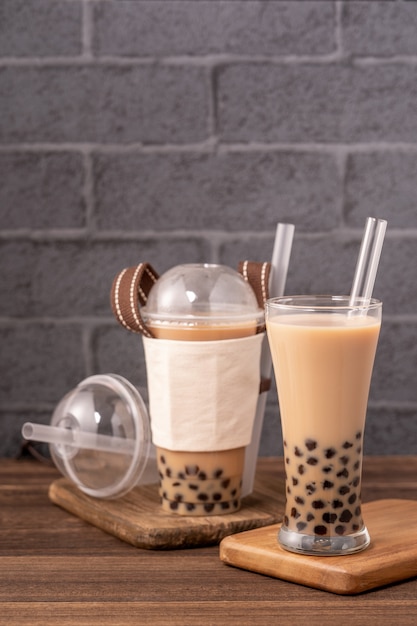 일회용 항목 개념으로 테이크 아웃 플라스틱 컵과 나무 테이블에 짚으로 인기있는 대만 음료 거품 우유 차