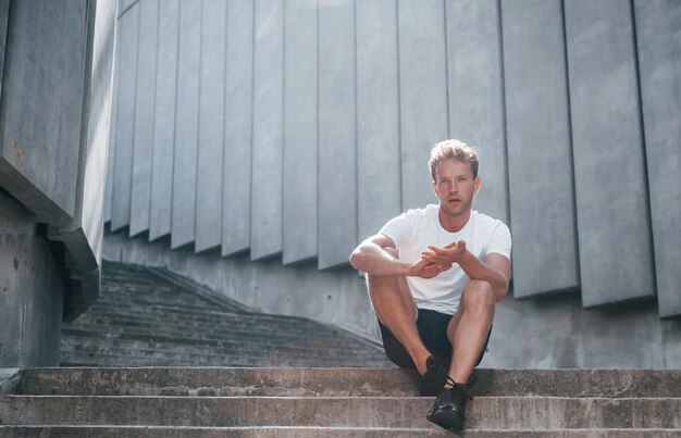 Takes a break Young man in sportive clothes have workout outdoors at daytime