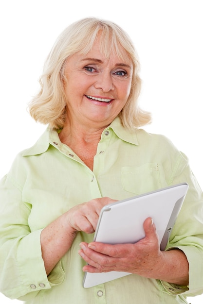 Taking advantages of digital age. Cheerful senior woman using digital tablet and smiling while standing isolated on white background