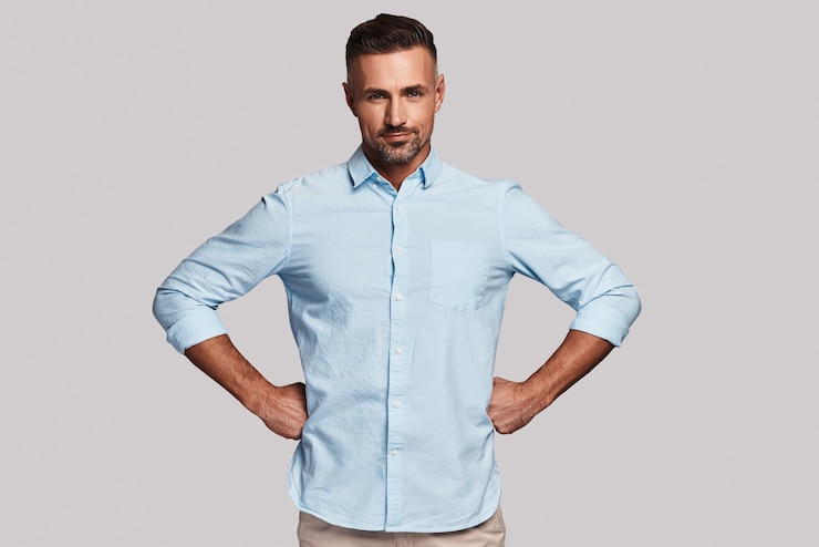 Photo taking everything seriously. handsome young man smiling and looking at camera while standing against grey background