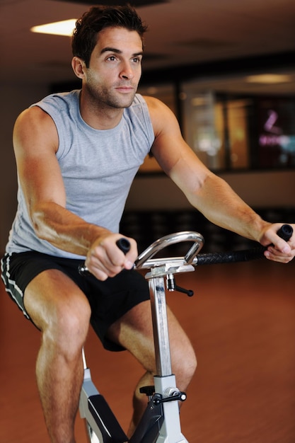 Taking his cycling to a new level A handsome young man wearing sport clothing and using a exercise bike at the gym