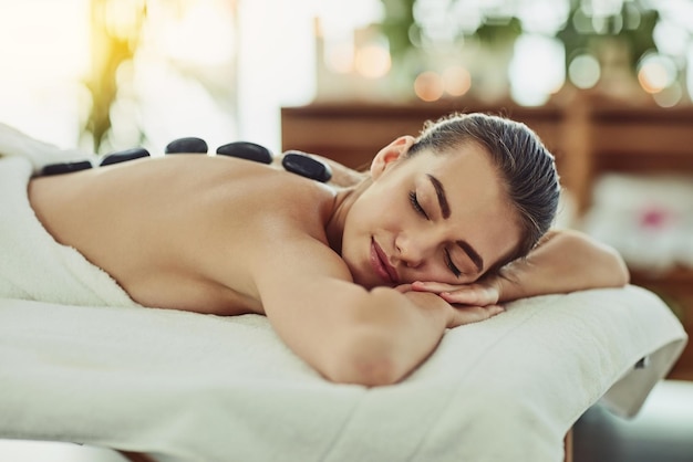 Taking it right to the muscles with heat Shot of an attractive young woman getting a hot stone massage at a beauty spa