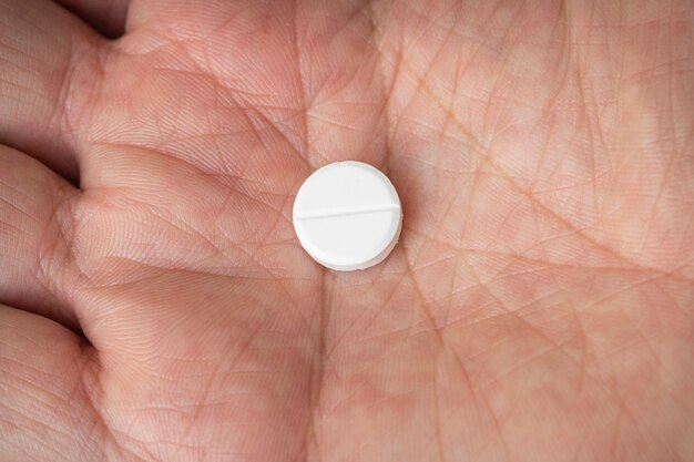 Taking medications. A round white tablet in the palm of your hand. white pill in men's hand.