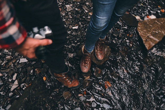 Отдохнуть минутку. Крупным планом вид молодой современной пары, стоящей на мокрой земле, наслаждаясь своим путешествием в горах