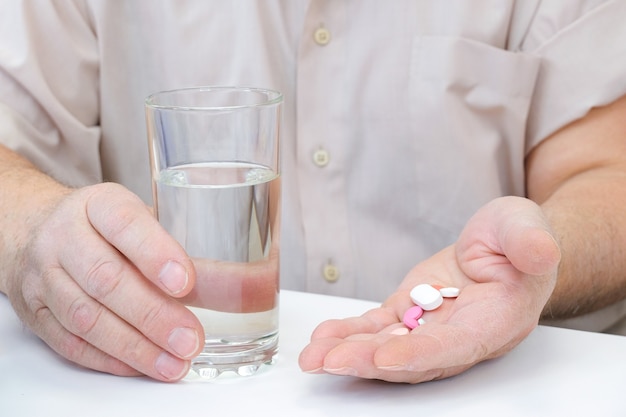 Taking pills, a glass of water in the hand of an elderly person. vaccination of an adult person in a hospital. healthcare concept, coronavirus vaccine