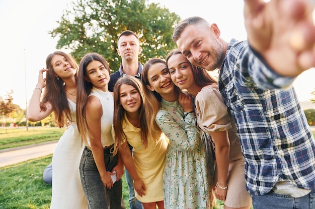 Taking a selfie Group of young people have a party in the park at summer daytime