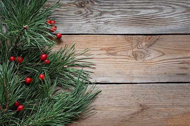 Takken van een kerstboom (grenen) met rozenbottels op een houten ondergrond. Kerstmis en Nieuwjaar