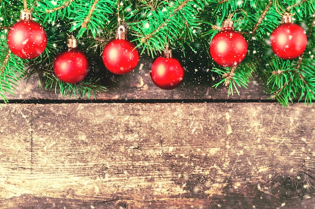 Takken van een kerstboom op oude planken. Kerst achtergrond. Kerst versiering. Nieuwjaar achtergrond. Xmax achtergrond. Afgezwakt beeld. Vallende sneeuw.