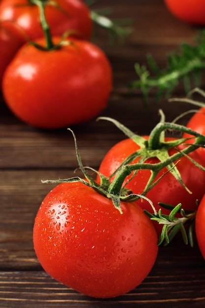 Takken van rijpe rode tomaten en takken van rozemarijn op donkere houten tafel