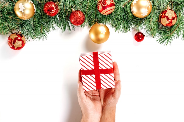 Takken van spar, speelgoed, mannelijke handen met een geschenk, rode witte doos met lint, geïsoleerd op wit. Isoleren. Vrolijk kerstfeest en een gelukkig nieuw jaar.