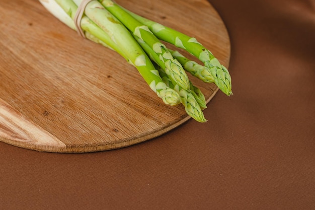 Takken van verse groene asperges op een houten bord bruine achtergrond bovenaanzicht Basistrendconcept met kopieerruimte