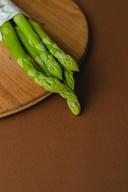 Takken van verse groene asperges op een houten bord bruine achtergrond bovenaanzicht Basistrendconcept met kopieerruimte