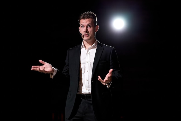 Photo talented successful motivational speaker, talking about happiness, self, success, empowerment, efficiency, health, and how to be more productive. large conference hall with light in background