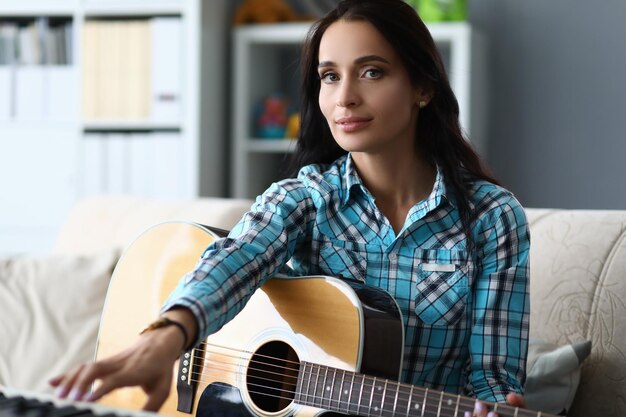 Foto giovane donna di talento che tiene la chitarra in mano a casa