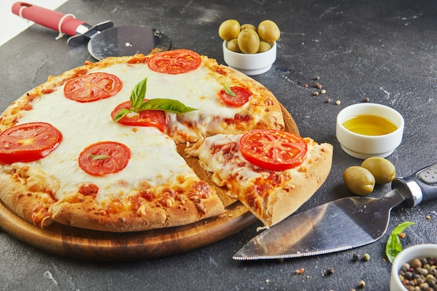 Талианская пицца и ингредиенты для приготовления пищи на черном бетонном фоне