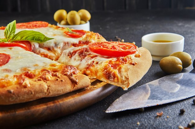 Talian pizza and ingredients for cooking on a black concrete background