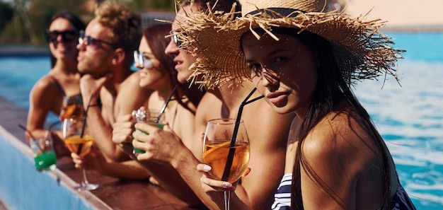 Talking and drinking Group of young happy people have fun in swimming pool at daytime