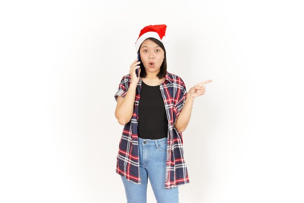 Talking on the phone and pointing aside of Asian Woman Wearing Red Plaid Shirt and Santa Hat