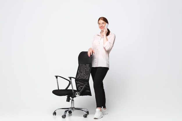 Talking phone. Young woman in casual wear on white background. Bodypositive character, feminism, loving herself, beauty concept. Plus size businesswoman during paperwork. Inclusion, diversity.