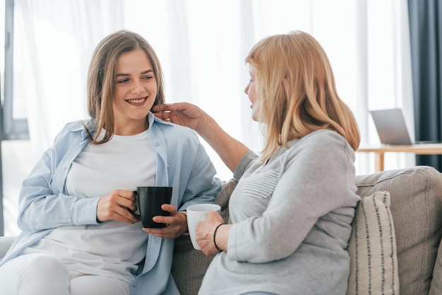 Talking with each other With cups of drink in hands Mother and daughter is together at home