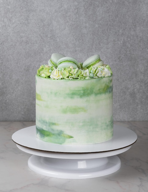 Foto torta alta con crema verde e decorazioni di macarons