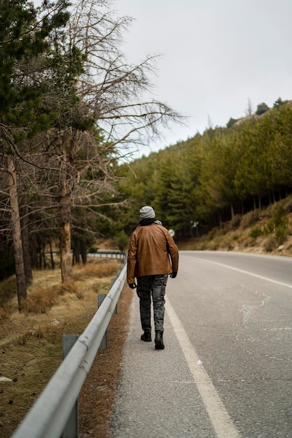 暖かい服を着てポーズをとって山にひげを生やした背の高い男