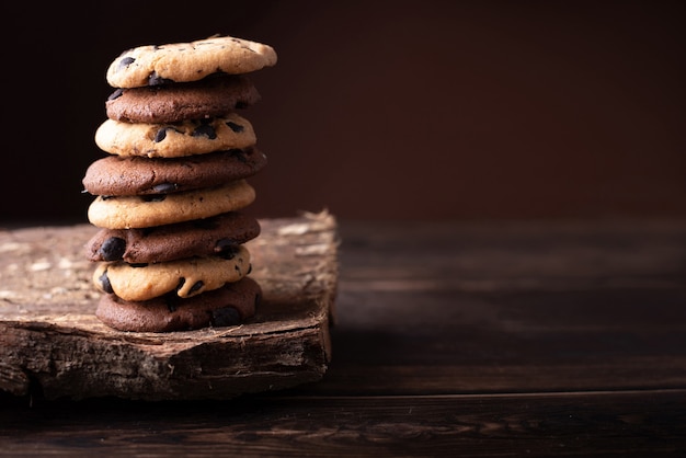 Tall Ñhocolate chip cookie tower on a dark wooden table..