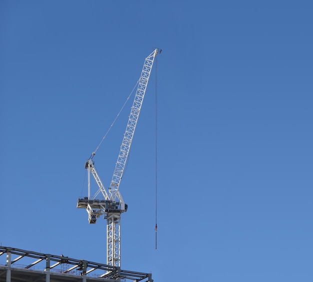 Photo tall hoisting tower crane on the top section being constructed of modern high skyscraper building