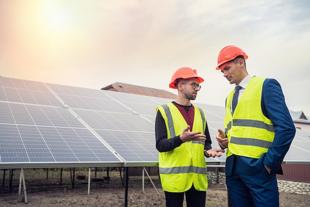 Tall men in work clothes are considering whether to install solar panels in the open air The concept of caring for solar panels under the sky