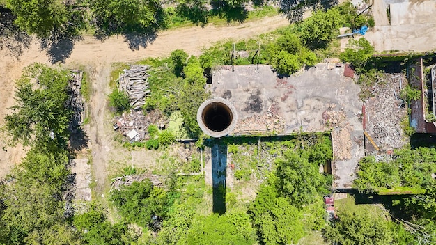 Tall smokestack silo opening from above aerial over abandoned rotting building farm