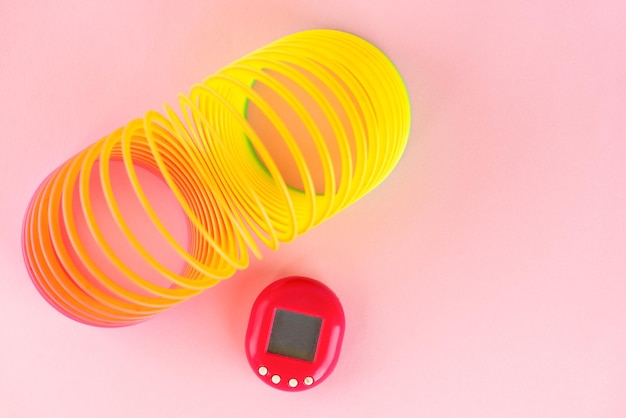 Photo tamagotchi toy with rainbow on a pink background popular games in the 90s top view