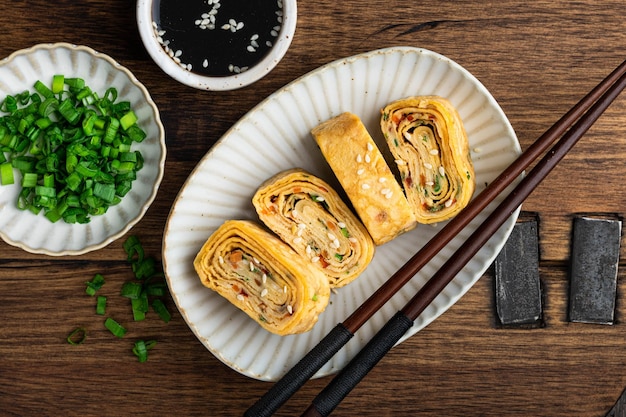 사진 다마고야키 일본식 오믈렛은 세라믹 접시 위에 올려져 있습니다.
