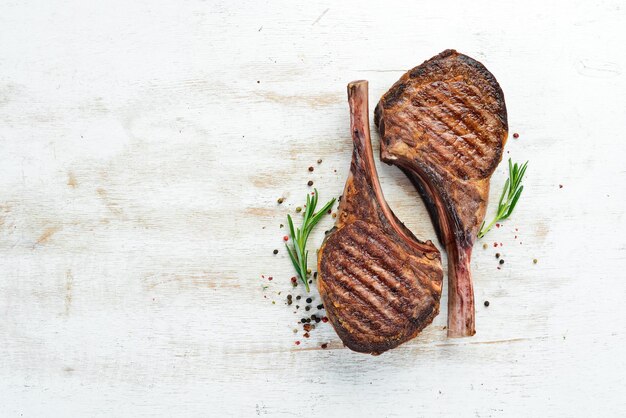 Tamahavk steak op het bot met specerijen en kruiden Op een witte houten achtergrond Bovenaanzicht Gratis kopieerruimte