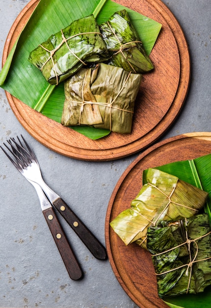 Tamales verpakt in bananen palmbladeren op houten platen