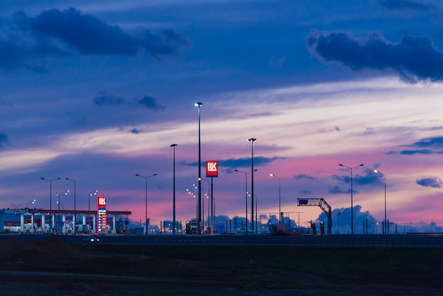 Taman, Rusland - oktober 2018: Lukoil tankstation op de Krim-brug bij zonsondergang, nacht. LUKOIL is een Russische oliemaatschappij.