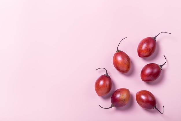 Tamarillo fruit on pink pastel paper background minimal flat lay