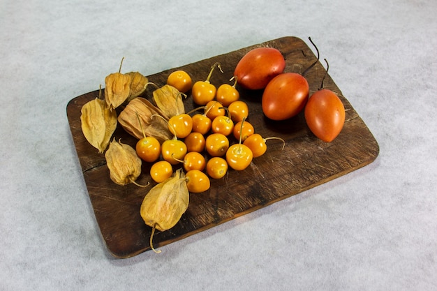 Tamarillo of boomtomaat op houten plank naast uvilla of aguaymanto physalis