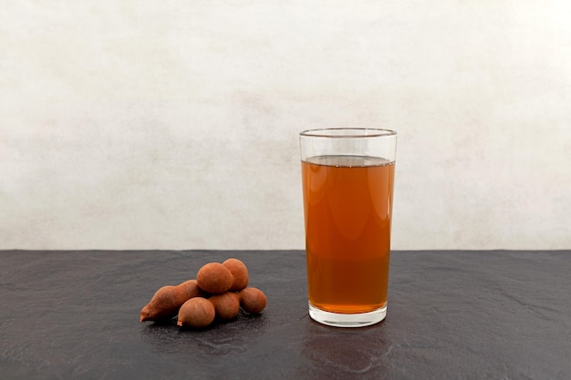 Тамариндовый напиток в высоком стакане, вид сбоку. Сок тамаринда. Травяной медицины.