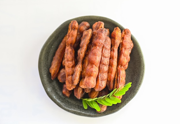 Tamarind sweet for food fruit ripe tamarinds on plate and white background Tamarind peel in plate tropical fruits summer top view