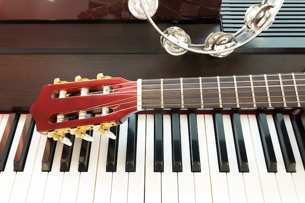 Photo tambourine and neck of guitar on piano keyboard.