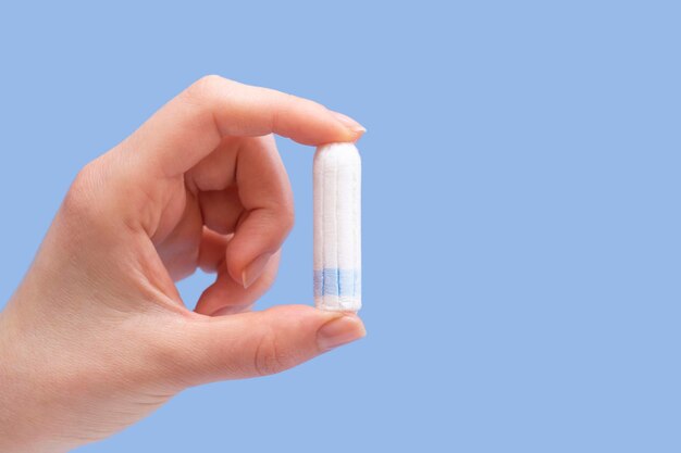 Tampon in female hands closeup On a blue background