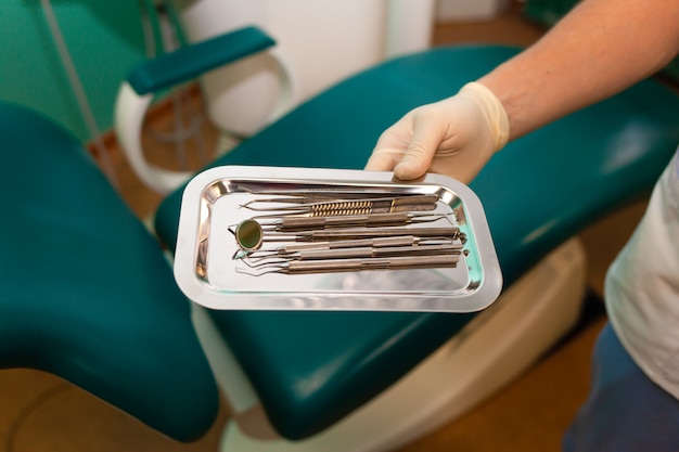Tandarts arts heeft veel tandheelkundige instrumenten in zijn handen. steriele tandheelkundige instrumenten close-up