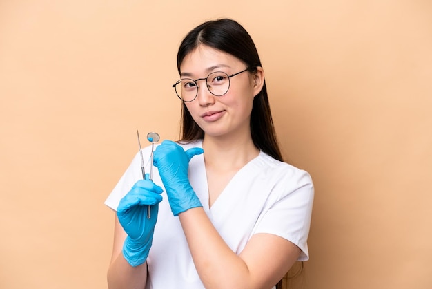 Tandarts Chinese vrouw met tools geïsoleerd op beige achtergrond trots en zelfvoldaan