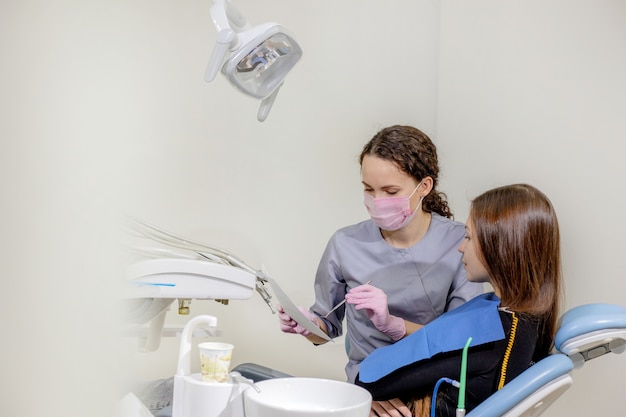 Tandarts de details van een foto van een x-ray tanden uit te leggen aan zijn patiënt in de kliniek.