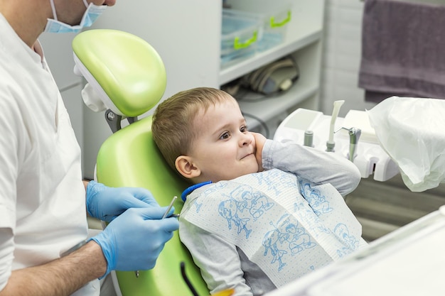 Tandarts die de tanden van de kleine jongen onderzoekt in de kliniek Tandprobleem