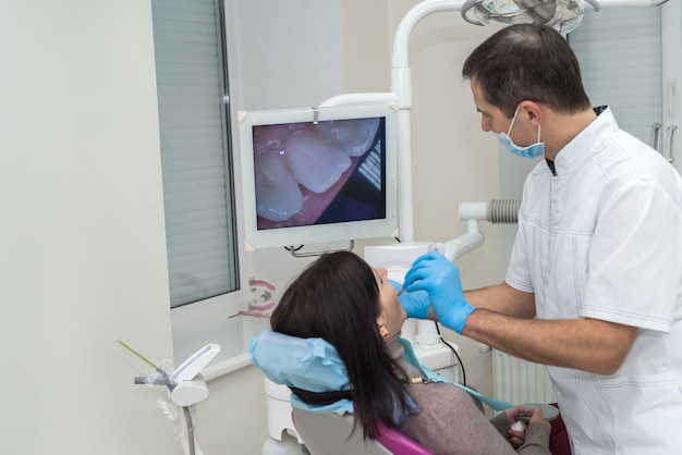 Tandarts die de tanden van de patiënt controleert met camera in de stomatologie